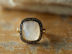 Luminescent rainbow moonstone is hand-set onto an 18 kt gold-plated band. The central stone is framed in rose-cut diamonds, which sparkle against oxidized sterling silver.