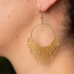 Illuminate your ensemble with the Golden Sun Earrings, a dazzling expression of craftsmanship and elegance. Each earring features a radiant gold circle, exquisitely framed by a shimmering gold fringe of miyuki glass beads, all intricately handwoven to perfection. Pair them with your favorite attire to create a look that shines from day to night. While these earrings stand beautifully on their own, they can be complemented by the Golden Sun Necklace, sold separately, to complete the resplendent s Gold Fringe Earrings In Brass, Gold Earrings With Beads For Celebration, Gold Fringe Drop Earrings, Gold Dangle Tassel Earrings For Celebration, Bohemian Gold Hoop Earrings For Celebration, Adjustable Gold Tassel Earrings With Fringe, Gold Beaded Brass Hoop Earrings, Gold Fringe Chandelier Earrings As Gift, Gold Beaded Earrings With Dangling Beads For Celebration