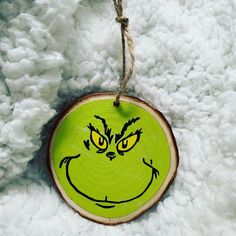 a green wooden ornament with a grin face drawn on it