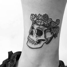 a black and white photo of a skull with flowers on it's side ankle