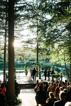 a wedding ceremony in the woods with sun shining down on the bride and groom standing at the alter