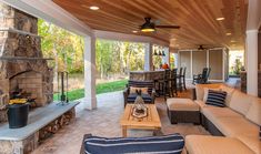 an outdoor living area with couches, tables and fireplace in the middle of it