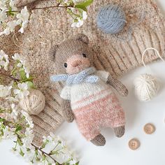 a knitted teddy bear is next to some balls of yarn