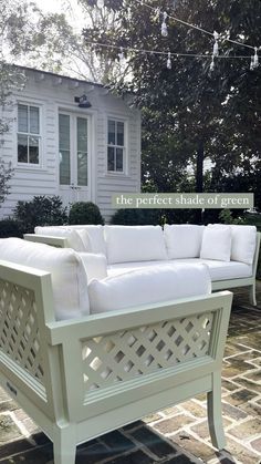 a white couch sitting on top of a brick patio next to a house and trees