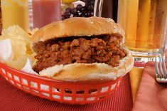 a chili beef sandwich in a basket next to some fries and fruit on the table