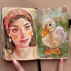 a woman's hand is holding an open book with two pictures of ducks on it