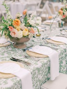 the table is set with flowers and place settings for guests to sit down at it