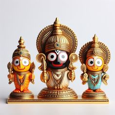 three small gold statues with eyes and body painted like hindu god's, one in the foreground