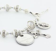 "A dazzling First Holy Communion bracelet, Confirmation bracelet, or Quinceanera bracelet. The ornate and delicate Rosary Bracelet has 10 rhinestone pearls to represent the Hail Mary beads and one larger rhinestone pearl as the Our Father bead. It comes with a Crucifix and a Miraculous Medal dangling near the clasp. It is available with or without an Engraved Disc and it comes with your choice of a Gift Message that is elegantly boxed for simple gift giving. Add an Engraved Disc - Select a Disc Engraved Silver Rosary Bracelet As Gift, Elegant Personalized Jewelry For Confirmation, Personalized Silver Rosary Bracelet For Confirmation, Elegant Personalized Bracelets For Confirmation, Elegant Silver Bracelet For First Communion, Elegant Silver Bracelets For First Communion, Elegant Silver Beaded Bracelets For First Communion, Elegant Personalized Rosary Bracelet For Confirmation, Personalized Silver Beaded Bracelets For First Communion