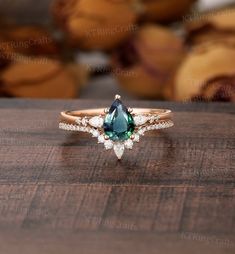 a green and white diamond ring sitting on top of a wooden table