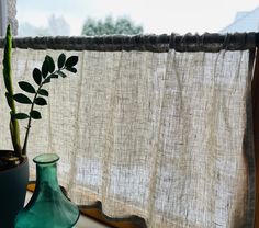 a green vase sitting on top of a window sill next to a potted plant