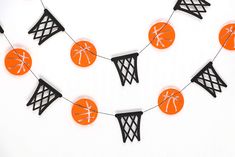 an orange and black basketball themed party banner with paper balls hanging from it's net