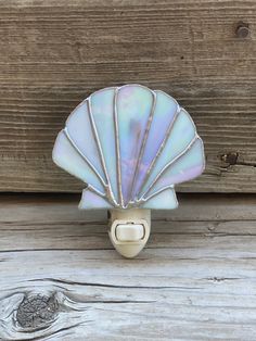 a shell shaped light switch cover on a wooden door handle with wood planks in the background