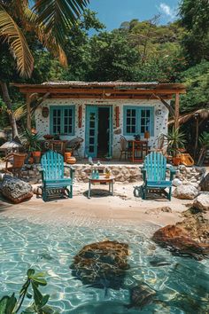 two blue chairs sitting in front of a small white house next to a pool with clear water