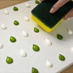 someone using a sponge to clean their mattress with green and white drops on the floor