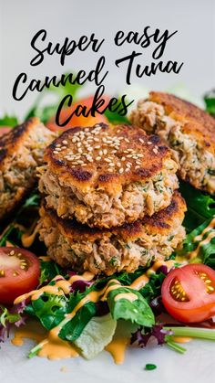 two crab cakes stacked on top of each other with lettuce and tomatoes in the background