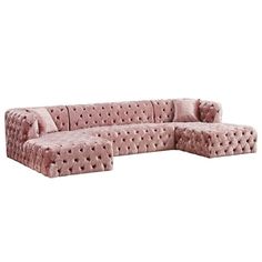 a pink velvet sectional sofa with pillows on the top and bottom, in front of a white background