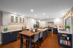 a large kitchen with white cabinets and wooden flooring, along with stainless steel appliances