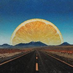 an orange cut in half sitting on the side of a road with mountains in the background