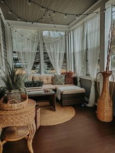 a living room filled with lots of furniture and windows covered in white drapes next to a wooden floor