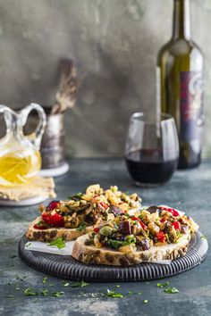 an open face sandwich on a plate next to two bottles of wine