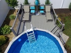 an above ground swimming pool with deck chairs and umbrella