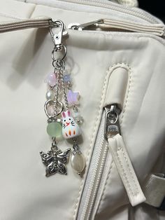 a close up of a white purse with charms on it