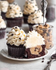 cupcakes with white frosting and chocolate chips are on a plate next to other cupcakes