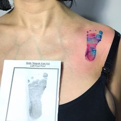 a woman's upper arm with a baby foot print on the left side of her chest