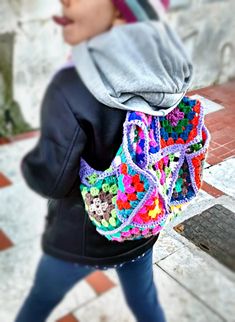 a woman carrying a colorful crocheted purse on her back