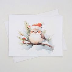 two cards with watercolor paintings of santa claus and a bird on the front one has a pine branch