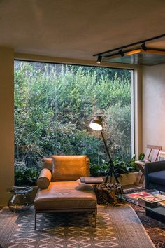 a living room filled with furniture and a large window covered in greenery behind it