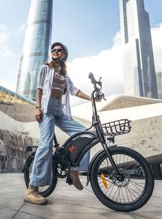 a woman standing next to her bike in front of some tall buildings and skyscrapers