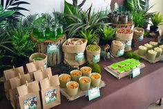 a table topped with lots of green plants and bags filled with food next to each other