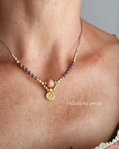 a close up of a woman wearing a necklace with gold beads and a medallion on it