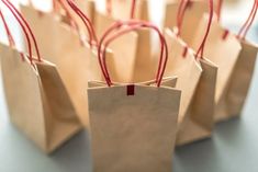 small brown paper bags with red string tied around the handles are sitting on a table