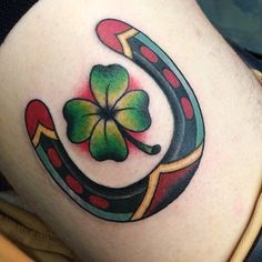 a shamrock tattoo on the side of a woman's thigh with a horseshoe and four leaf clover