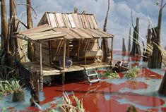 a house on stilts in the water with red paint all over it's surface