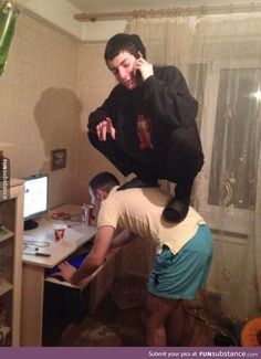 a man standing on top of another man's head in front of a computer desk