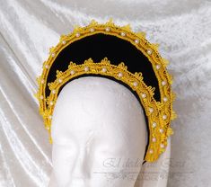 Medieval flat headband.  This headband is made with a semi-rigid leatherette base, lined with blue velvet and  adorned with golden silk trimmings and synthetic pearls.  All the tiaras can be accompanied by a veil.  Normally, the veils I send are broken white (ecru), but if you want any other colour, tell me when you buy.  The short veil has a size of 50 x 70 cm.   The long veil has a size of 75 x 120 cm.  For any other size of the veil, you must tell me the measurements and I will tell you the price.  This type of headband is made with a 3 mm. thick leather base, which gives it the degree of rigidity and at the same time flexibility, suitable for its use.  This leatherette can be lined with any type of fabric you wish, and can be finished with trimmings, biases, or any other form of finish Elegant Gold Costume Hats And Headpieces For Ceremonial, Adjustable Gold Crown Headband, Gold Tall Crown Headpiece Handmade, Gold Crown With Pinched Shape For Festivals, Gold Regal Headpiece With Tall Crown, Medieval Crown Headpiece For Festival, Gold Costume Hats With Round Crown, Medieval Crown Style Festival Headpiece, Adjustable Gold Costume Headpieces