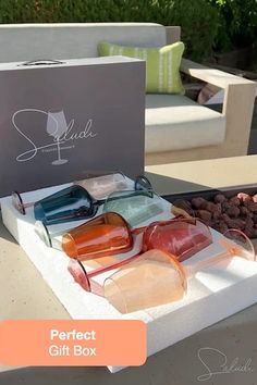 an assortment of glasses sitting on top of a table next to a box with the words perfect gift box