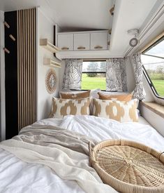 a bed with pillows and blankets in front of a window that has a basket on it