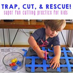 a young boy sitting at a table cutting out pieces of paper with scissors and tape