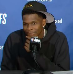 a man wearing a hat sitting in front of a microphone