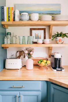 a kitchen with blue cabinets and shelves filled with plates, bowls, cups and other items