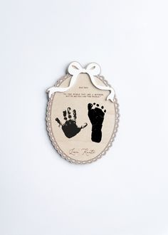 a hand and foot print on a plaque with a ribbon hanging from the back of it