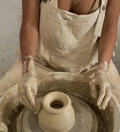 a woman in an apron working on a potter's wheel