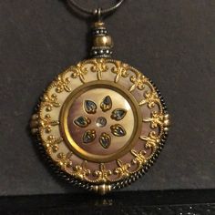 an ornate gold and white locke necklace on a black surface, with flowers in the center