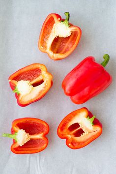 four red peppers cut in half on a white surface