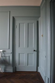 an empty chair sits in front of the door to a room with gray walls and wooden floors